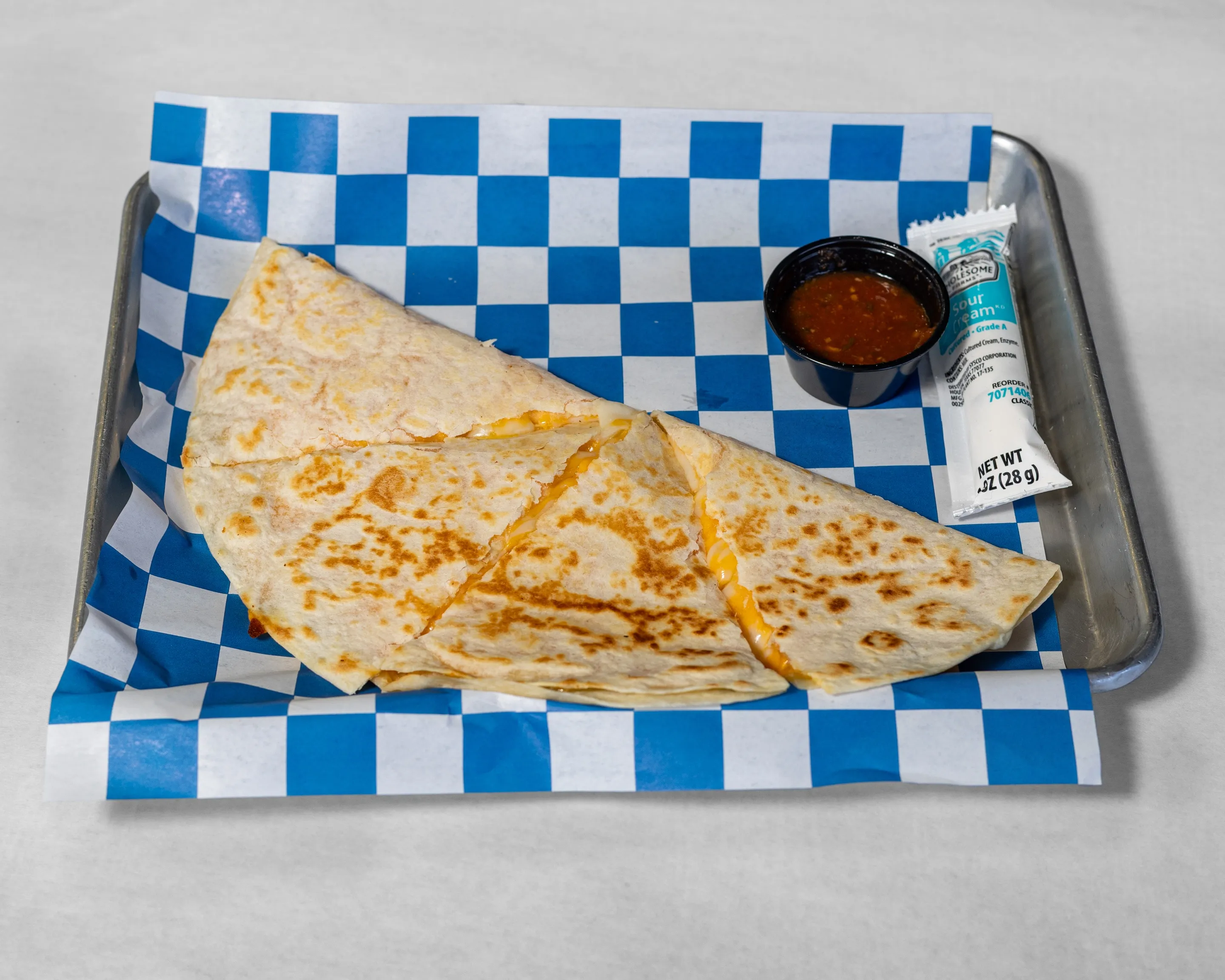 Cheese Quesadilla from Timmy Jon’s BBQ in Dade City, FL, built by Double Barrel Smoker, shown with stacked wood for authentic Texas-style smoking.